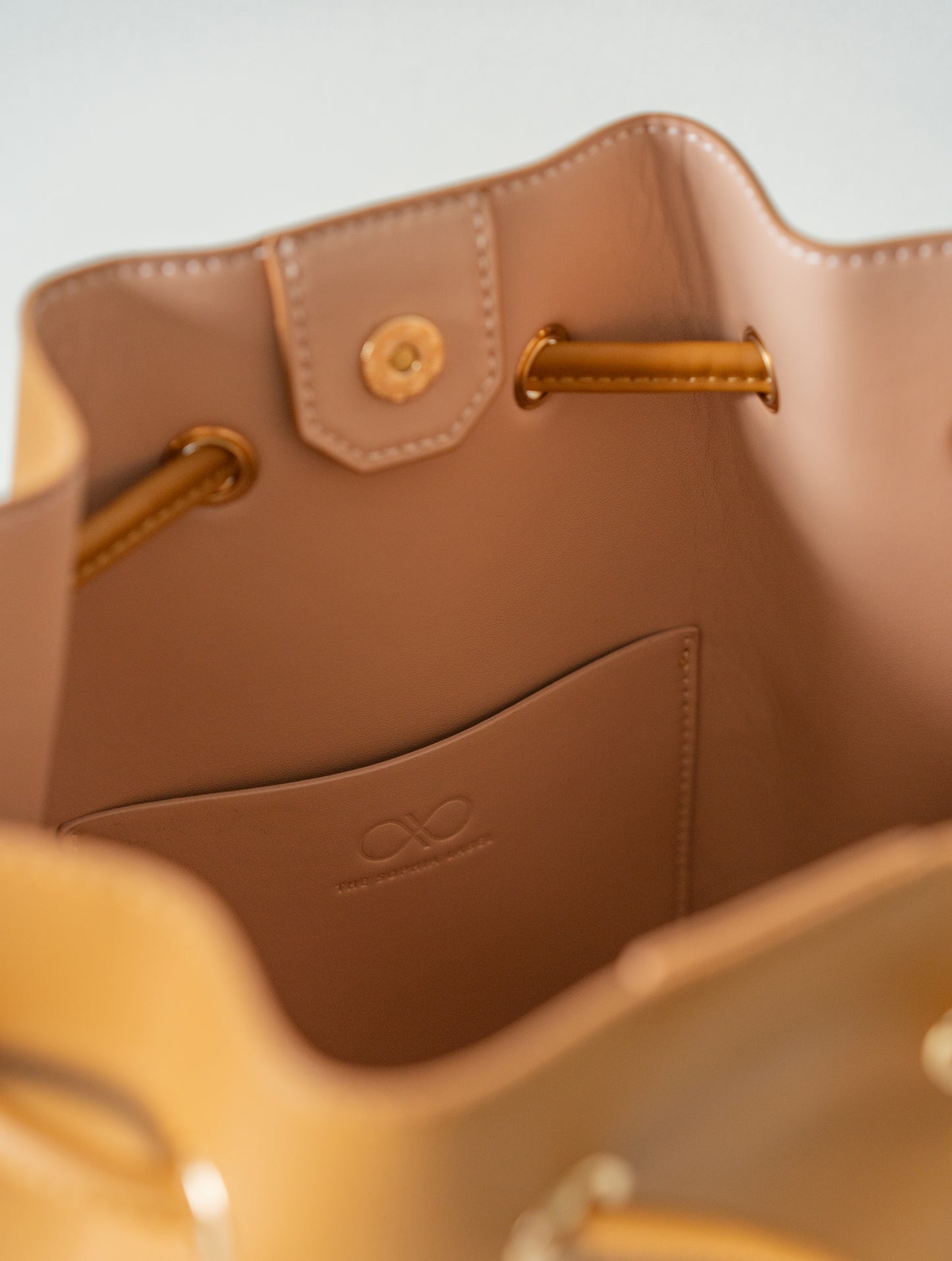 MINI REINA MAGIC BUCKET BAG IN CAMEL